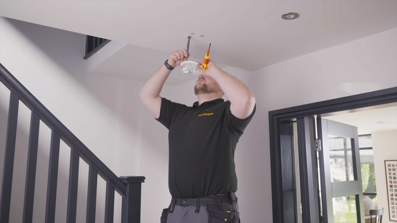 An installer fitting a FireAngel alarm in a home