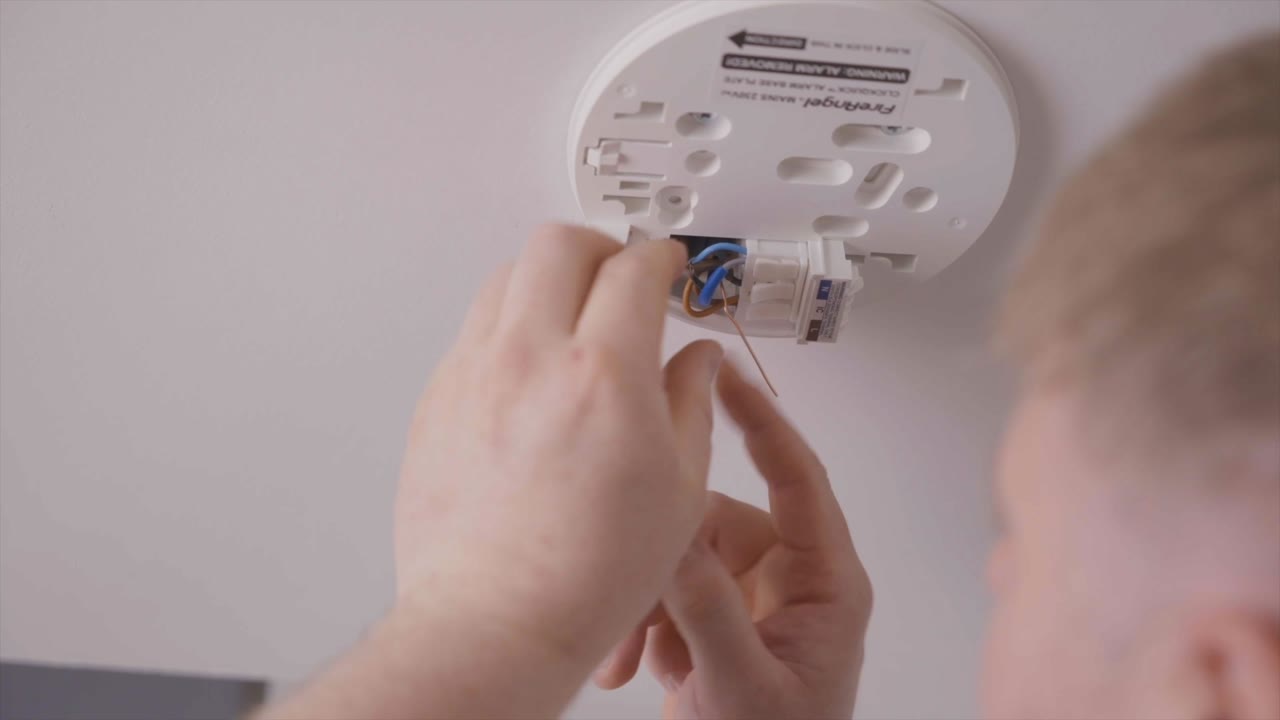 A professional installer wiring a FireAngel alarm base